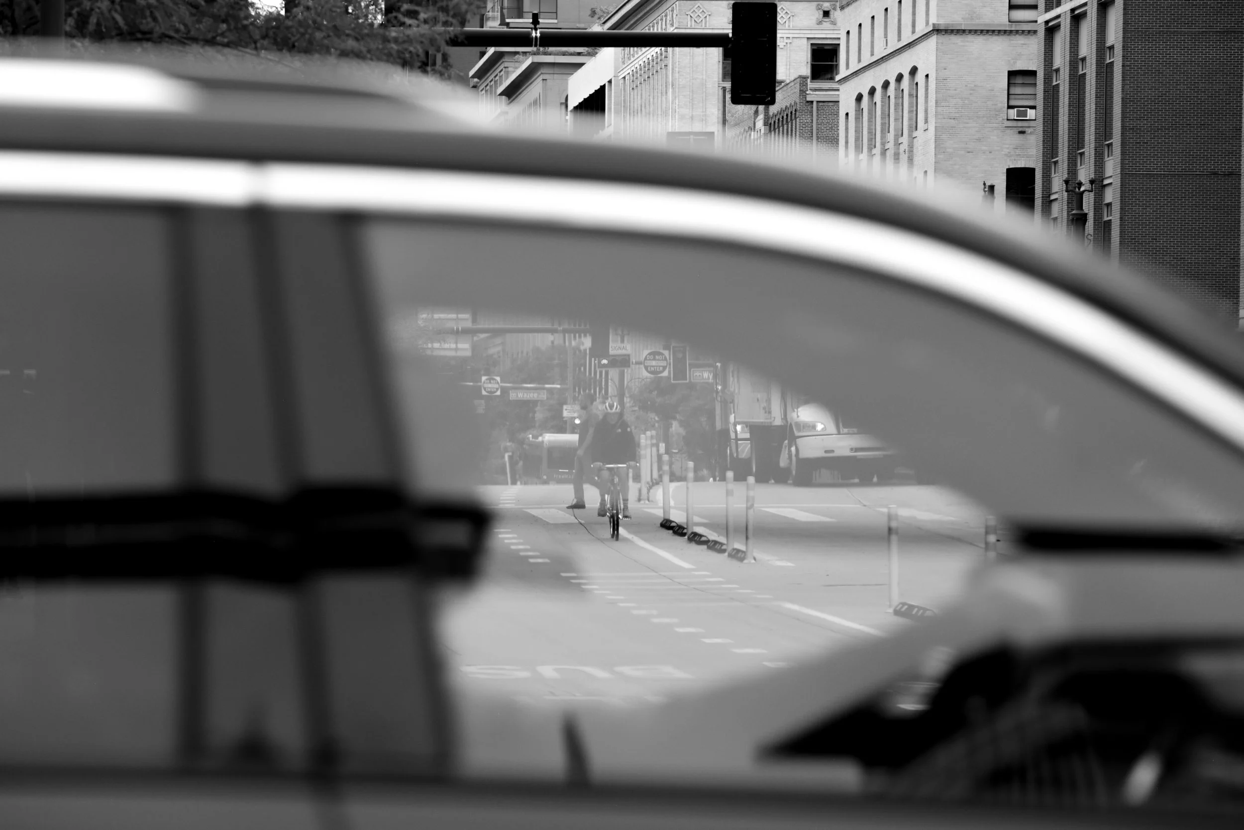 Black and white photo of a cyclist riding in a bike lane on a Denver city street